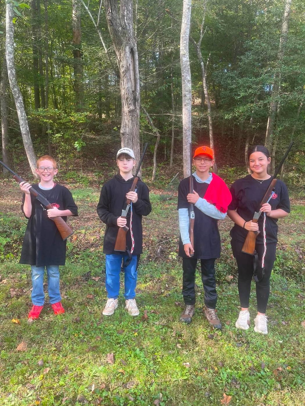 Four young hunters holding shotguns in the woods before a small game outing.